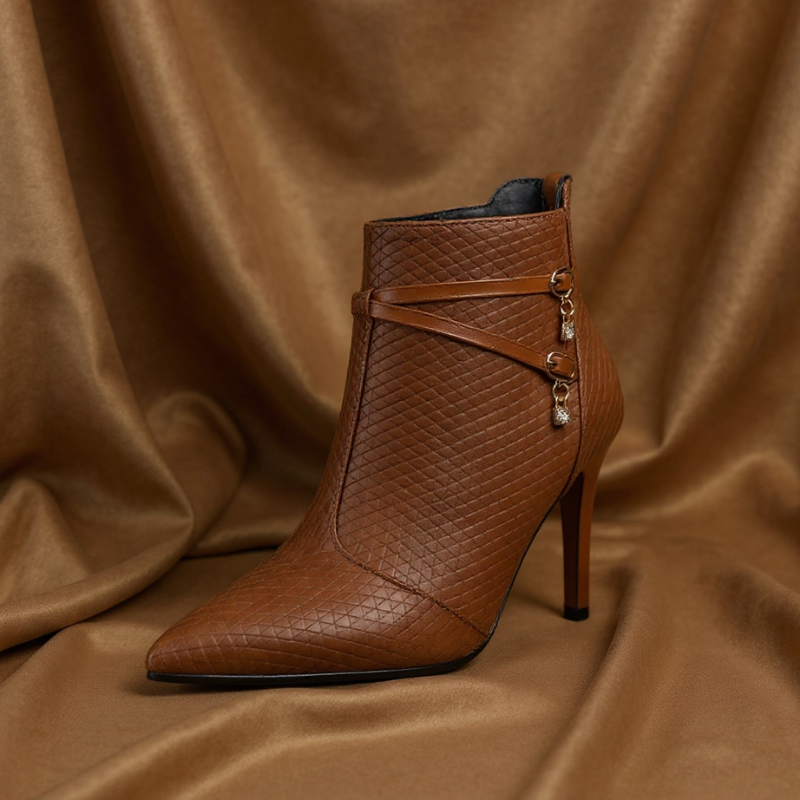 Faux leather stiletto heel boots with crossed straps, crystal charm accents and a pointed toe
