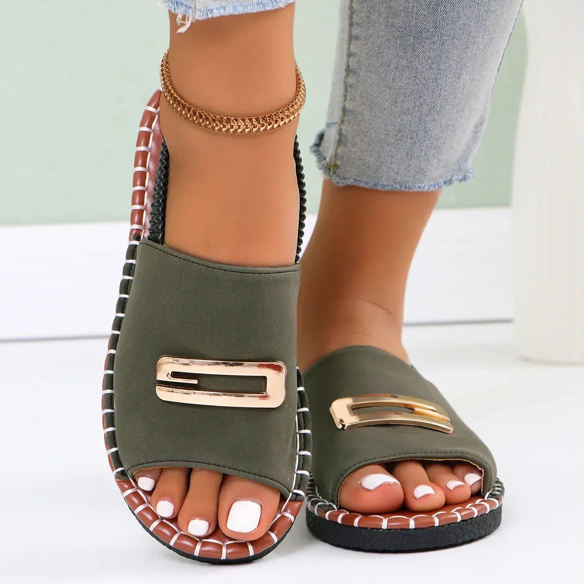 Flat sandals with gold buckle accent and contrast stitching in neutral tones